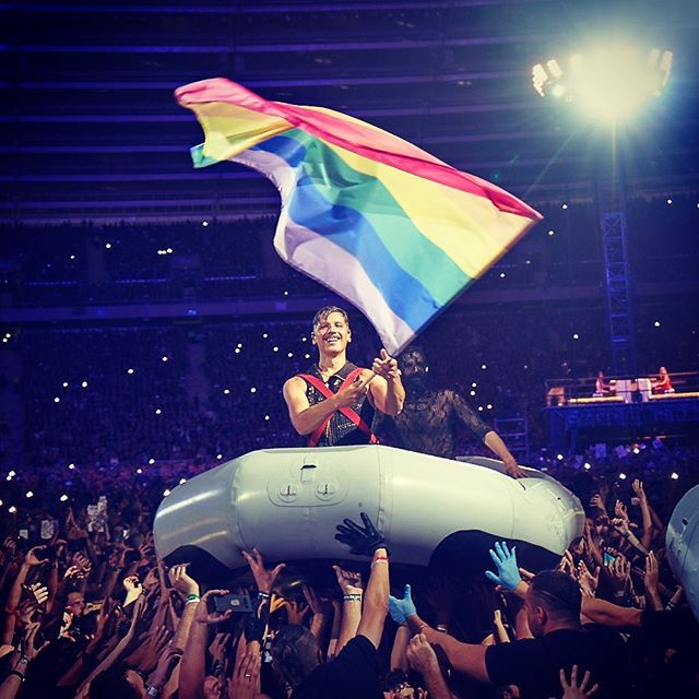 The drummer of Rammstein, waving the rainbow flag on a boat above the audience